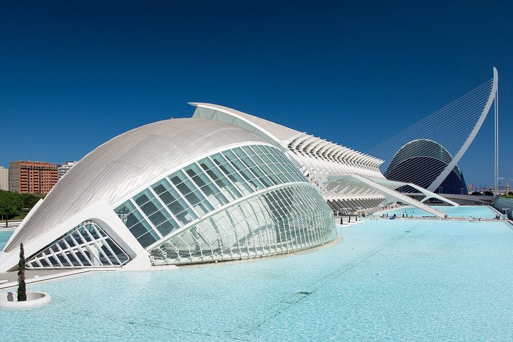 The Hemisferic reflected in a turquoise pool under a clear sky