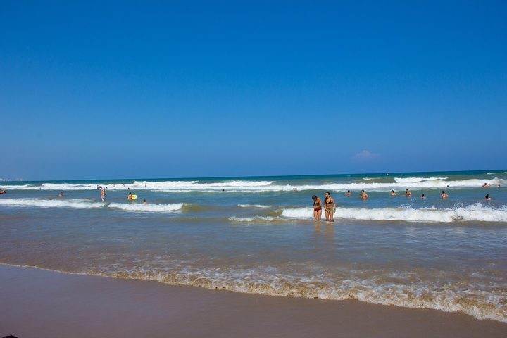 Golden sand and shallow surf with bathers along the shoreline