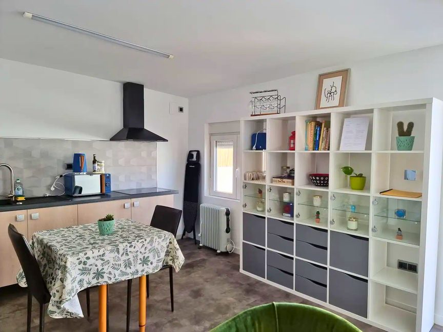 A kitchen with an induction hob, extractor, microwave and a dining table laid with a patterned cloth